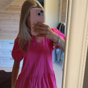 Rosa kortklänning från Zara - Supersöt rosa klänning från Zara med puffiga korta ärmar och volangdetaljer. Modellen är luftig och har en avslappnad passform, perfekt för varma dagar. Tillverkad i mjuk bomull som känns skön mot huden.