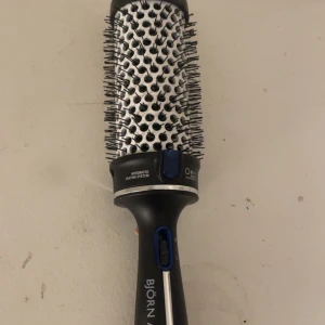 Björn Axén Tools värmeborste - Säljer en svart och silver värmeborste från Björn Axén Tools med integrerat värmesystem. Rund borste med täta borst och blå detaljer, perfekt för att styla och forma håret med volym. Ergonomiskt handtag och enkel knapp för temperaturkontroll.