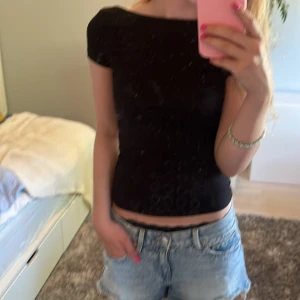 Svart croppad topp från Gina Tricot - Svart croppad topp från Gina Tricot med korta ärmar och rund halsringning. Sitter tight och har en enkel, stilren look som passar till jeans eller kjol. Perfekt för dig som gillar minimalistisk stil och vill ha en basic topp i garderoben.