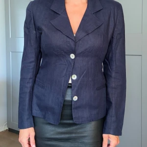 Kavaj i linne med axelvaddar - Vintage mörkblå kavaj i 100% linne från ”Cool”. Figursydd med pärlemor knappar. 