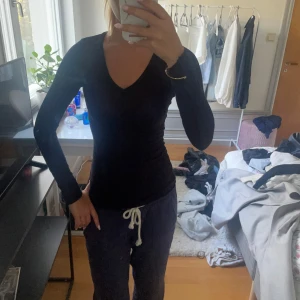 Svart långärmad v-ringad tröja - En svart långärmad tröja med v-ringning och tight passform. Perfekt basplagg som funkar till allt och är enkel att styla. 