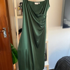 Grön satinklänning från Vila - Supersnygg grön långklänning från Vila i glansigt satinmaterial. Klänningen har draperad framsida och smala axelband, vilket ger en elegant och trendig look. 🫧