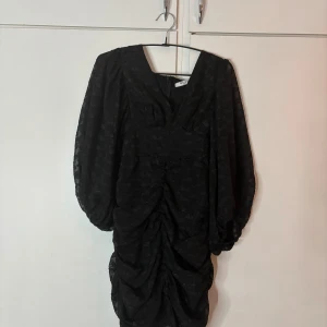 Festlig klänning från NA-KD - Supersnygg svart kort klänning från NA-KD med puffiga trekvartsärmar och coolt strukturmönster. Klänningen har rynkade detaljer och en markerad midja. Storlek 36, den är helt oanvänd med prislapp kvar. 