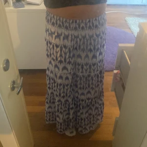 Blåvit långkjol från Gina Tricot - Snygg långkjol från Gina Tricot i blått och vitt med ett unikt mönster. Kjolen har resår i midjan och är tillverkad i ett lätt och luftigt material, perfekt för varma dagar. Lång och luftigt. Bara andvänt 1-2 gånger. Pris kan diskuteras.