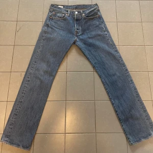 Levi's 501 blue jeans W31 L32 - blå denim Byxorna har fem fickor, knappgylf och ikoniska detaljer som nitar och läderpatch bak. Perfekta för dig som gillar tidlös stil och vill ha ett par riktigt schyssta jeans.