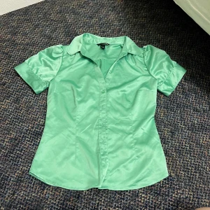 Grön kortärmad skjorta - Snygg grön skjorta från H&M. Skjortan har korta ärmar med knappar, klassisk krage och figurnära passform. 🩷