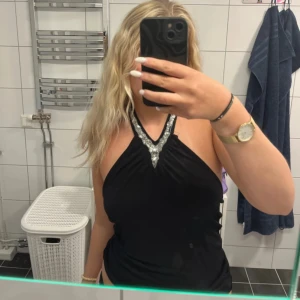 Festlig halterneck topp med silver detaljer - Svart halterneck tröja med silverdetaljer och öppen rygg. Toppen är i strl M från Only. Knappt använd och i bra skick! Perfekt till fest!