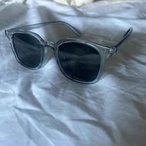 Transparenta blå solglasögon - Snygga solglasögon med transparent blå båge och svarta glas. Klassisk fyrkantig form som ger en cool vibe. Perfekta för att lyfta din stil under soliga dagar. Lätta och bekväma att bära hela dagen.