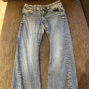 Ljus blå utsvängda Gina Tricot  jeans med slitna benslut - Klassiska blå utsvängda jeans med slitna, fransiga benslut. Jeansen har fem fickor, bälteshällor och tydliga sömmar. Perfekta för dig som gillar en lite mer vintage och chill look.