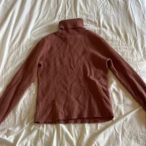 Rostbrun turtleneck ribbad polotröja - Säljer en turtleneck ribbad polotröja i en snygg rostbrun färg. Tröjan har lång ärm och hög polokrage, perfekt för lager-på-lager. Materialet är stickat och ger en mysig känsla. Enkel att matcha med jeans eller kjol för en chill look.