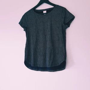 Svart prickig blus från H&M XS - Svart blus från H&M Basics i storlek XS med små vita prickar över hela tyget. Modellen har rund halsringning, korta ärmar och något längre bakstycke. Perfekt för en chill och stilren look.  Helt & fint skick