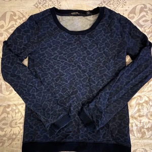 Blå leopardmönstrad tröja Maison Scotch - Snygg långärmad tröja från Maison Scotch i mörkblått med leopardmönster. Tröjan har rund halsringning, ribbade muddar och är tillverkad i mjukt bomullsmaterial. Perfekt för dig som gillar djurmönster och vill ha en cool vardagslook. Väldigt fin💕💕