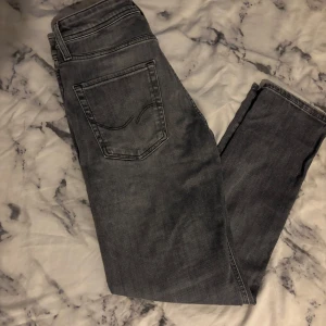 Grå jeans från Jack & Jones - Säljer ett par helt nya grå jeans i modellen Tapered/Mike. Storlek 29 i midjan och 30 i längd. Jeansen sitter lite lösare upptill och smalnar av vid benen