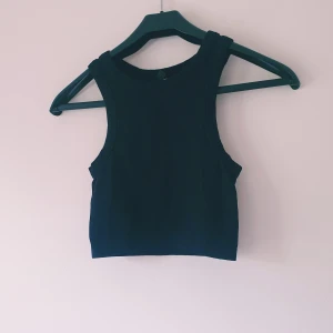 Svart ribbad croppad linnetopp - En svart croppad linnetopp med ribbad struktur och breda axelband. Toppen är ärmlös och har en enkel, stilren design som passar perfekt till jeans eller kjol. Snygg och enkel att matcha med olika outfits.  Helt skick dock små noppror
