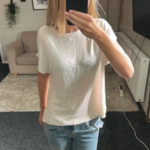 Vit kortärmad tröja från H&M BASIC - Enkel och stilren vit tröja från H&M BASIC i storlek S. Modellen är rak med korta ärmar och rund halsringning. Tröjan har ribbad kant nedtill och är tillverkad i ett mjukt, tunt material som känns skönt mot huden.