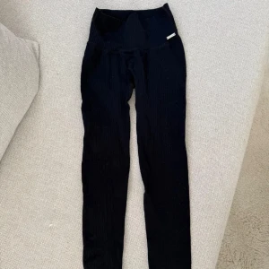 Svarta ribbade leggings med hög midja - Säljer ett par svarta ribbade leggings från aimn med hög midja. De är stretchiga och formar sig fint efter kroppen.