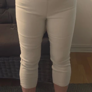 Beiga croppade byxor från Freequent - Snygga beiga byxor från Freequent med bred resår i midjan för extra komfort. Byxorna har fickor bak och är tillverkade i ett mjukt bomullsmaterial. Perfekta för en fräsch och stilren look. Ankellånga.