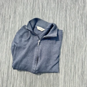 Gran Sasso grå zip-kofta i ull - Snygg grå kofta från Gran Sasso med hel dragkedja och hög krage. Tillverkad i mjuk ull, perfekt för lager-på-lager. Klassisk och stilren design med ribbade muddar och lång ärm. Passar dig som gillar en clean look.