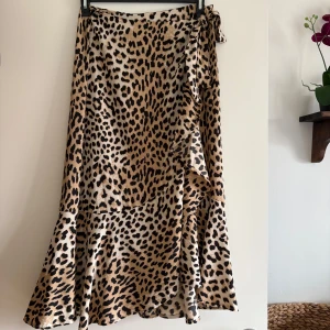 Leopardmönstrad omlottkjol med volang - Snygg långkjol med leopardmönster och omlottmodell. Kjolen har volangdetaljer och knyts i midjan för en cool och trendig look.