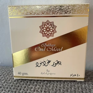 Bukhoor Oud Mood 40g - Bukhoor Oud Mood från Ard Al Zaafaran i en elegant fyrkantig ask med guldiga detaljer. Doften är orientalisk och träig, perfekt för att skapa en lyxig atmosfär hemma. Förpackningen är vit med guldmönster och rymmer 40 gram rökelse.
