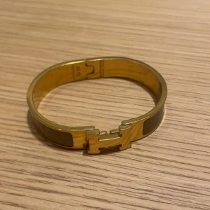 H armband - Snyggt guldarmband med ikoniskt H-spänne framtill. Armbandet är i metall med blank finish och har en stilren, klassisk design som verkligen sticker ut. 