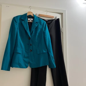 Le Suit set kavaj + byxa grönbla - Le Suit set kavaj + byxa grönblå, US8, motsvarar M enligt Le Suit. Kavajen har klassisk krage, tre knappar och fickdetaljer framtill. Byxorna är raka och stilrena. 