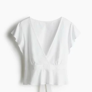 Vit omlottopp från H&M Divided - Helt ny och oanvänd vit omlottopp från H&M Divided i luftig linnemix. Toppen har korta ärmar, v-ringning och knyt i midjan som ger en snygg siluett. Perfekt till sommaren och enkel att styla med både jeans och kjol.