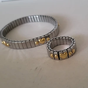 Vintage Nomination jewellery set - Both the bracelet and the ring have stretch for easy use. The ring has a heart and dots. The bracelet has hearts, stars, and dots. The design part is gold and the silver part is stainless steel. Very small signs of use upon very close inspection. Comparable jewellery from nomination currently avaible would cost 225 euros (ring €96, bracelet €129). However these specific designs are discontinued   Pick up Obbola, can be brought to ica maxi, nus, vasaplan, or capio hc dragonen. Shipping avaible
