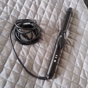 Svart locktång med digitala knappar - En svart locktång med digitala knappar för temperaturreglering. Tången har ett klassiskt klämgrepp och lång sladd för smidig styling. Passar dig som vill fixa snygga lockar snabbt och enkelt. Materialet är plast och metall.