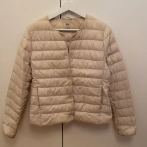 Ultra light down jacka - Jättefin beige ultra light down jacka från Uniqlo! Knappar framtill för att stänga, två fickor framtill och en innerficka. Lätt och perfekt till sommar,vår, tidig höst. Klarar av regn. Använd mycket men fortfarande i bra skick förutom en del fläckar  och lite missfärgat speciellt vid ärmöppningen och nacken . Påse medkommer.  Köpt för 749kr. skriv priv för bilder mer bilder på defekterna