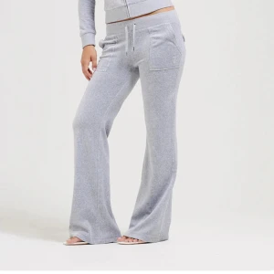 Grå mjukisbyxor med snörning - Superbekväma grå mjukisbyxor med bootcut och snörning i midjan. Byxorna har stora fickor fram och bak, samt en liten broderad logga på ena fickan. Perfekta för chill dagar eller när du vill vara extra comfy. Dom har även lite smuts nedanför som inte går bort, jag har även använt dom ett par gånger men används inte nå mer.