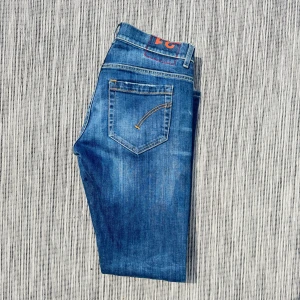 Dondup jeans - Snygga blå jeans med klassisk femficksdesign och kontrastsömmar på bakfickan. Jeansen har en mellanblå tvätt och en rak passform som funkar till det mesta. Perfekta för dig som gillar en enkel men stilren look.!AI BESKRVINING! Om ni vill ha fler bilder eller om ni har andra funderingar och frågor skriv.