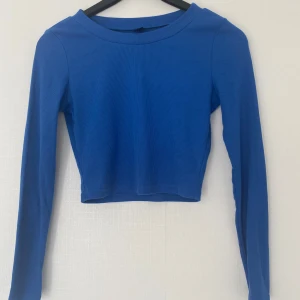 Blå croppad långärmad topp Shein - Säljer en blå croppad långärmad topp från Shein i ribbad bomullsmix. Enkel och stilren modell med rund halsringning och tight passform. 