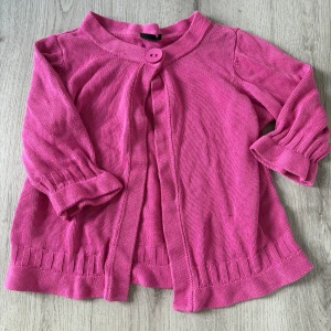 Rosa kofta från Isolde XL - Snygg rosa kofta från Isolde i stickad bomull. Koftan har en stor dekorativ knapp framtill, trekvartsärmar med ribbade muddar och en avslappnad passform. Perfekt att slänga över en topp för en färgklick i vardagen.