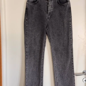 Gråa raka jeans med hög midja NA-KD stretchjeans storlek 40 - Snygga grå jeans med rak passform och hög midja. Jeansen har klassisk femficksdesign och stängs med knappar framtill. Perfekta för dig som gillar en clean och tidlös look. Materialet är denim och färgen är tvättad grå. NA-KD storlek 40. Stretchjeans. 