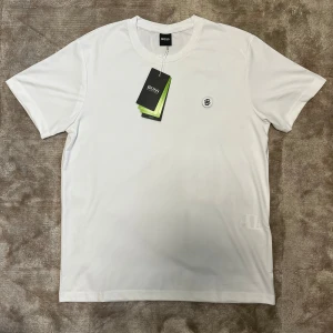 BOSS T-Shirt - Säljer en vit BOSS T-shirt med liten logga på bröstet. Tröjan är helt sjuk i kvalité - känns lyxig, sval och är nästan omöjlig att skrynkla. Väldigt stilren och passar till allt, både vardag och finare tillfällen.  Pris kan diskuteras!
