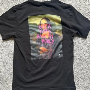 Svart t-shirt med tryck xs - Svart t-shirt i bomull med korta ärmar. På ryggen finns ett stort färgglatt tryck med text i rosa och gult, och framtill står det 'NEVER BROKE AGAIN' i vitt. Skön passform och perfekt för dig som gillar streetwear vibes.