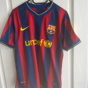 FC Barcelona Messi 10 matchtröja Nike - Säljer en klassisk FC Barcelona fotbollströja med Messi 10 på ryggen. Tröjan är randig i rött och mörkblått med gula detaljer, klubbmärke och sponsortryck framtill. Tillverkad i lätt och ventilerande Dri-FIT-material, perfekt för fotbollsplanen eller samlingen.