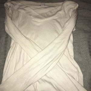 Ribbad vit långärmad tröja - Säljer en stilren vit ribbad tröja med lång ärm och v-ringad hals. Tröjan är i ett mjukt, stretchigt material och har en klassisk passform som funkar till många olika looks. Perfekt för lager-på-lager under hösten eller våren. Passar någon som har S också