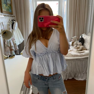 Ljusblå blus med volang - Superfin ljusblå blus med resor i midjan 