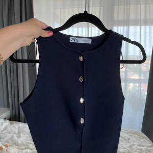 Mörkblå ärmlös topp från Zara - Snygg mörkblå ärmlös topp från Zara med raka linjer och fyra silvriga knappar framtill. Tjockare material som ger en exklusiv känsla. Använd en gång. 