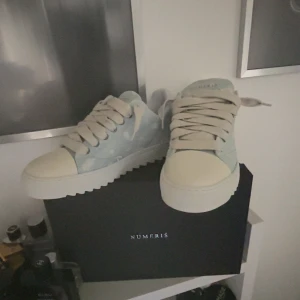 Ljusblå sneakers från NUMERIS - Snygga ljusblå sneakers från NUMFRIS med vit tå och sula. Skorna har breda vita snören och en cool, räfflad sula som ger extra edge. Ovandelen är i textil med diskreta slitningar för en trendig look. Perfekta för dig som gillar stilrena men unika sneakers. Storlek 44 men kan passa 44.5. Om du har en pris på huvudet skriv till mig så kan vi lösa. 