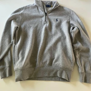 Grå half zip tröja från Polo Ralph Lauren - Snygg grå långärmad tröja från Polo Ralph Lauren med half zip och klassisk broderad logga på bröstet. Mjuk insida och ribbade muddar. Perfekt för lager-på-lager och chill vardagsstil. Väldigt bra skick, pris kan diskuteras😊