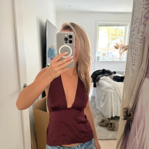 Vinröd halterneck linnetopp - Säljer en vinröd halterneck linnetopp som är perfekt som fest topp eller sommar topp, med djup v-ringning, åtsittande passform och öppen rygg. Toppen är från Gina Tricot och köpt förra sommaren