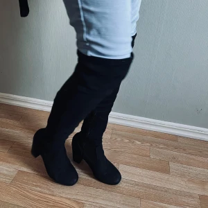 Svarta overknee stövlar - Snygga svarta overknee stövlar i mocka med klack och dragkedja på insidan. Perfekta för att ge en stilren look till din outfit.