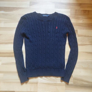 Mörkblå stickad tröja från Ralph Lauren - Säljer en snygg mörkblå stickad tröja från Ralph Lauren med klassiskt kabelstickat mönster. Pris kan diskuteras!