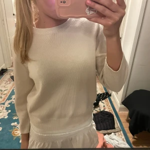 Vit stickad tröja - Säljer en stilren vit stickad tröja med rund hals och långa ärmar. Perfekt för en enkel och klassisk look. Tröjan har en ribbad kant vid ärmslut och nederkant.
