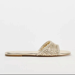 Guldiga sandaler - Snygga guldiga sandaler med en elegant flätad ovandel. Perfekta för sommarens alla tillfällen. De har en platt sula och en öppen design som ger en luftig känsla. Aldrig använda, köpta på zara förra sommaren🥰💓