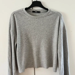 Grå croppad tröja från Bik Bok - Säljer en stilren grå croppad tröja från Bik Bok. Tröjan har långa ärmar och en rund halsringning, perfekt för en avslappnad look. Passar bra till både jeans och kjol. Dessutom väldigt skönt tyg. Perfekt för höst och vår!