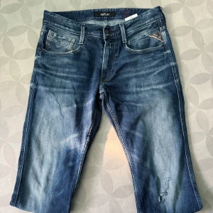 Replay jeans med fet tvätt 30/32 - Snygga blå jeans från Replay med en klassisk femficksdesign och lätt slitna detaljer. De har en knappgylf och är tillverkade i ett bekvämt denimtyg. Perfekta för en avslappnad stil.